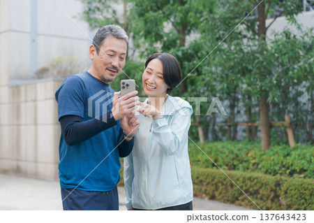 一對穿著運動服的情侶正在看手機。 137643423