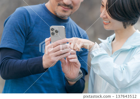 一對穿著運動服的情侶正在看手機。 137643512