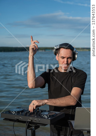 Caucasian man works as a DJ on the beach. Caucasian man works as a DJ on the beach. 137643553