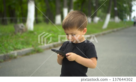 Child walking on park path smiling while holding smartphone 4k Child walking on park path smiling while holding smartphone 4k 137644302