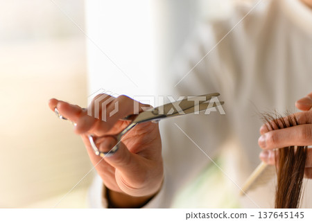 理髮師用剪刀剪頭髮。 137645145
