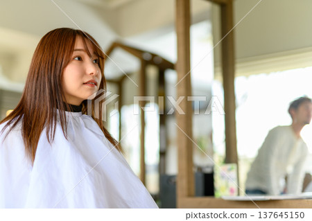 A woman getting her hair styled at a hair salon. 137645150