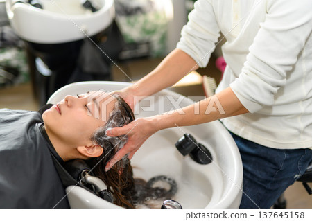 A hairdresser washes hair at the shampoo station. A hairdresser washes hair at the shampoo station. 137645158