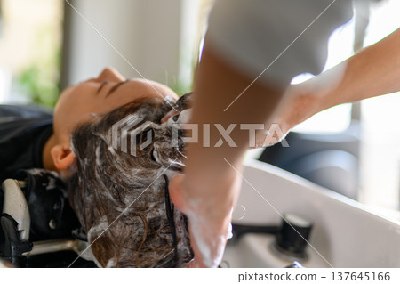 A hairdresser washes hair with shampoo. A hairdresser washes hair with shampoo. 137645166