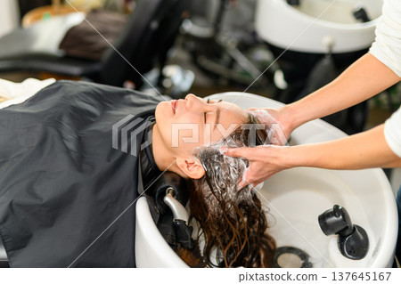A hairdresser shampooing a hair 137645167