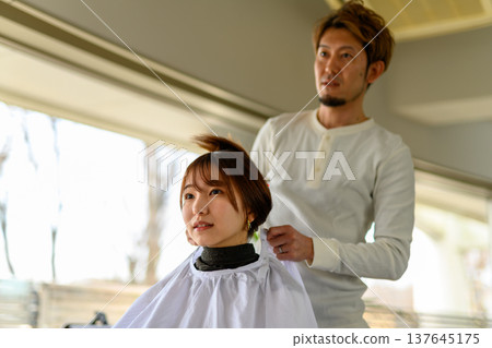 A hairdresser styles a female customer's hair. A hairdresser styles a female customer's hair. 137645175