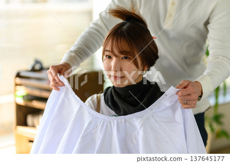 理髮師給顧客披上披肩。 137645177