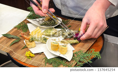 A scene of a chef preparing Japanese cuisine, plating tempura. A scene of a chef preparing Japanese cuisine, plating tempura. 137645254