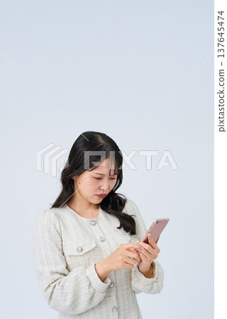 A young woman looking at a smartphone screen with a troubled expression 137645474