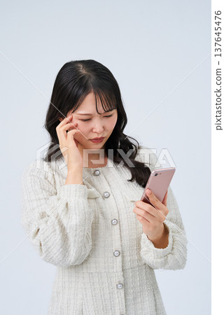 一位年輕女子帶著不安的表情看著智能手機屏幕 137645476