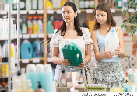 Woman with teen daughter view trademark sign on label, pick eco friendly liquid detergent 137646053
