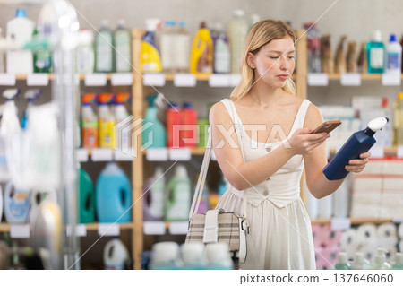 Girl buyer scans qr code on glass cleaner spray label Girl buyer scans qr code on glass cleaner spray label 137646060