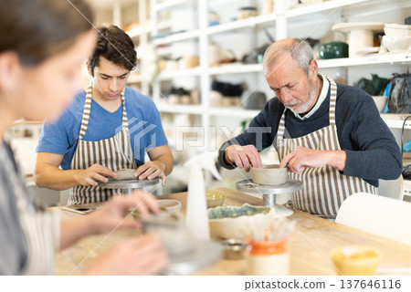 During working day, three pottery workshop workers sculpt from clay, form final product During working day, three pottery workshop workers sculpt from clay, form final product 137646116
