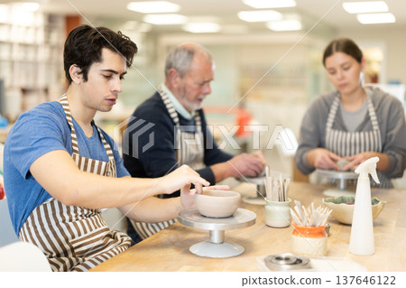Young man sculpts ceramic piece in workshop 137646122