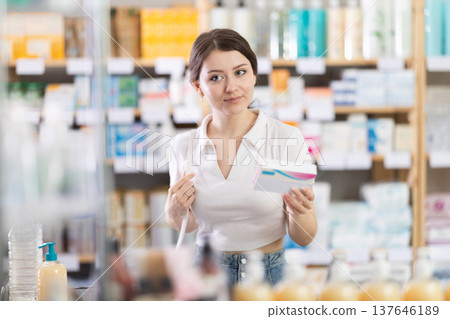 Young woman chooses pills at pharmacy Young woman chooses pills at pharmacy 137646189
