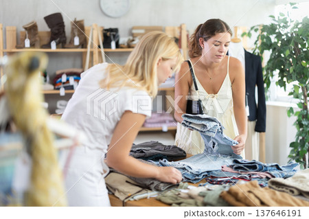 Two young women choosing trousers in store Two young women choosing trousers in store 137646191