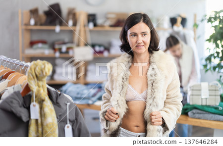 Woman try on fur jacket in front of mirror in clothes store, semi naked body 137646284