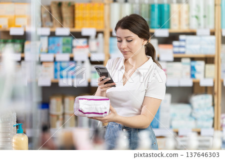 Young woman scans panty liners with phone in drugstore 137646303