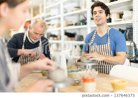 During working day, three pottery workshop workers sculpt from clay, form final product During working day, three pottery workshop workers sculpt from clay, form final product 137646373