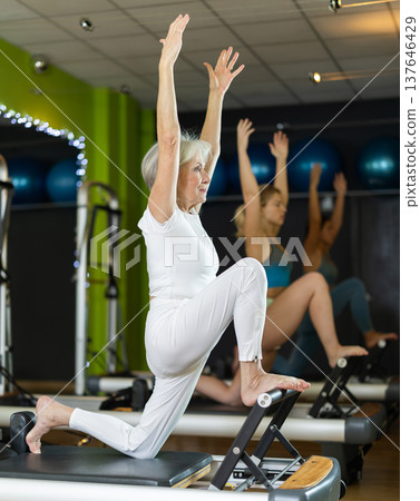 Mature woman actively doing Pilates exercises 137646429