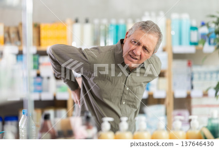 Older man experiencing sharp back pain while shopping in pharmacy 137646430