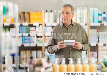 Elderly man in a pharmacy chooses pills Elderly man in a pharmacy chooses pills 137646432