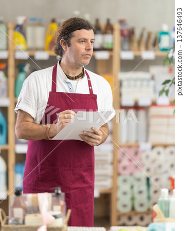 Adult man seller conducting inventory in store 137646493