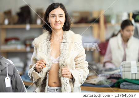 Adult woman trying on fur coat in store 137646587