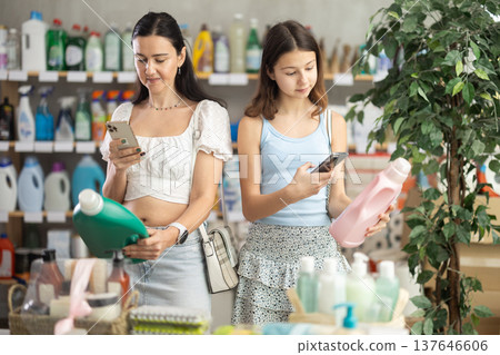 Woman with teen daughter buyer scans qr code on liquid laundry powder label Woman with teen daughter buyer scans qr code on liquid laundry powder label 137646606