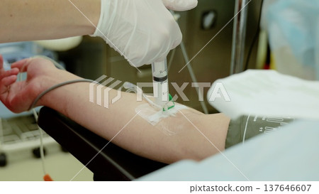 Healthcare professional administering intravenous medication, wearing protective gloves during surgical procedure, supporting patient treatment with precision and care 137646607