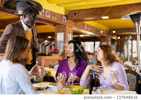 Smiling men invite women to dine for their table in restaurant Smiling men invite women to dine for their table in restaurant 137646616