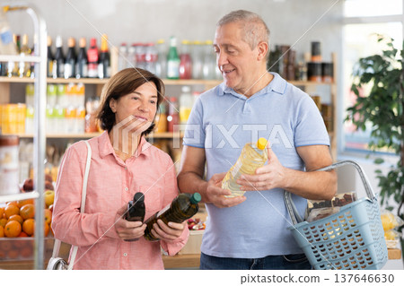 Mature couple buyer looks thoughtfully at bottles of vegetable oil 137646630