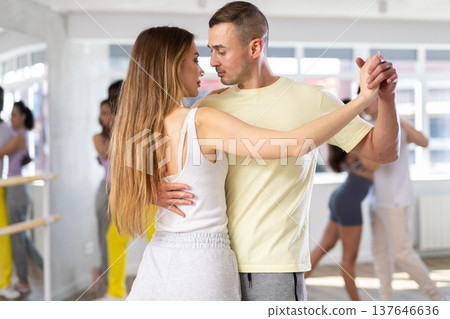 Young man and woman practicing salsa dance in pair in training hall Young man and woman practicing salsa dance in pair in training hall 137646636