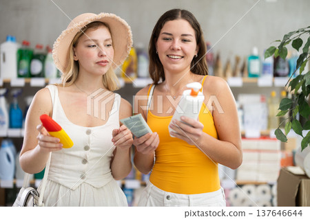 Two friends girls view trademark sign on label, pick eco friendly sunblock cream 137646644