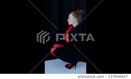 Professional model posing in studio, wearing red tights, gloves, black dress with heels. Dark background emphasizing sleek silhouette and dramatic side profile Professional model posing in studio, wearing red tights, gloves, black dress with heels. Dark background emphasizing sleek silhouette and dramatic side profile 137646647