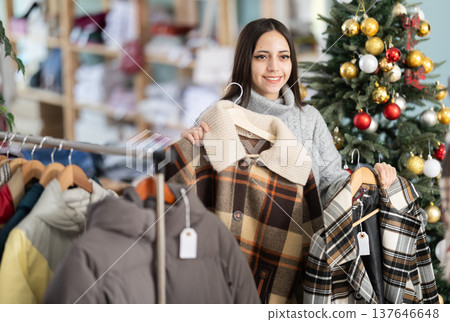Female shopper chooses coat or jacket in clothing store before Christmas Female shopper chooses coat or jacket in clothing store before Christmas 137646648