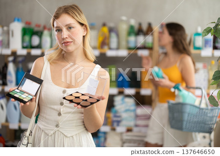 Young girl choosing cosmetics while other choosing something in background Young girl choosing cosmetics while other choosing something in background 137646650