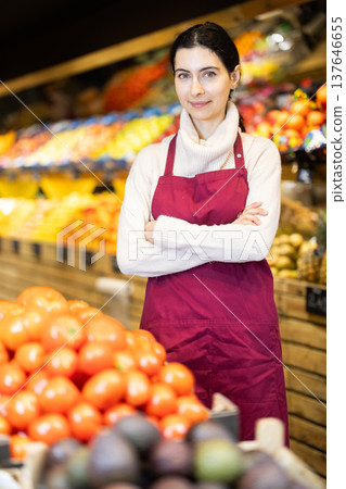 Young woman seller offering tomatoes in vegetable shop 137646655
