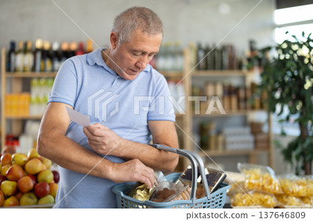 Elderly man buying groceries from shopping list in store 137646809