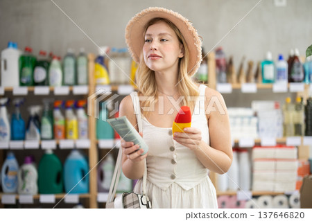 Young girl choosing tanning lotion in self-care products store Young girl choosing tanning lotion in self-care products store 137646820