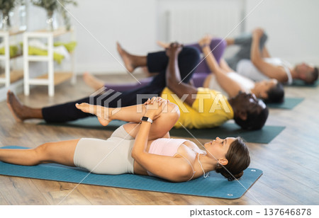 Young woman doing yoga in group in studio Young woman doing yoga in group in studio 137646878