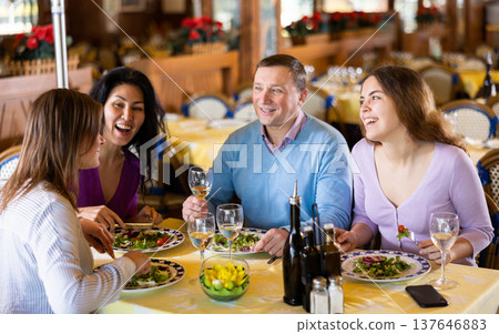 Adult men and women having friendly meeting at dinner in restaurant Adult men and women having friendly meeting at dinner in restaurant 137646883