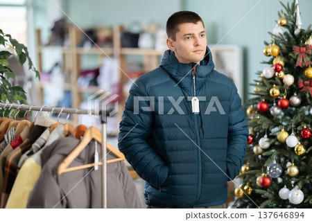 Guy customer is trying on down jacket in store, X mas Eve 137646894