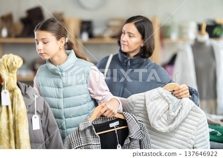 Mother and teen daughter looks at products in store and selects coat or jacket. 137646922
