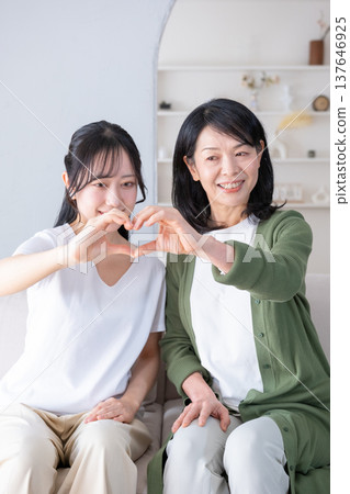 Mother and daughter making a heart shape with their hands Mother and daughter making a heart shape with their hands 137646925