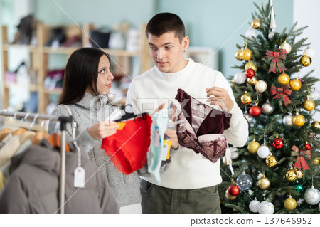 Couple chooses lingerie for girl in a clothing store during Christmas celebrations. Couple chooses lingerie for girl in a clothing store during Christmas celebrations. 137646952