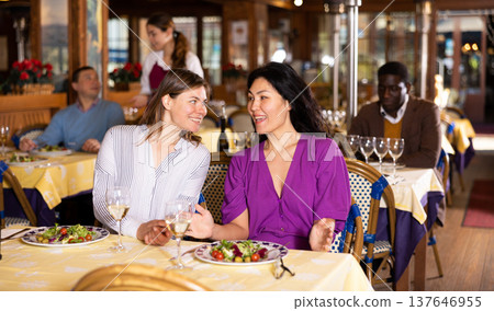 Women having meal and talking in restaurant 137646955