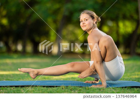 Girl in park on green grass of lawn performs Chakorasana Girl in park on green grass of lawn performs Chakorasana 137646964