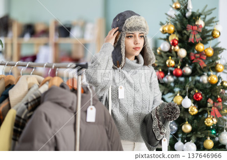 Young girl choosing winter hat in clothing store Young girl choosing winter hat in clothing store 137646966
