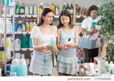Mom and daughter choosing shampoo while man choosing something in background Mom and daughter choosing shampoo while man choosing something in background 137646988